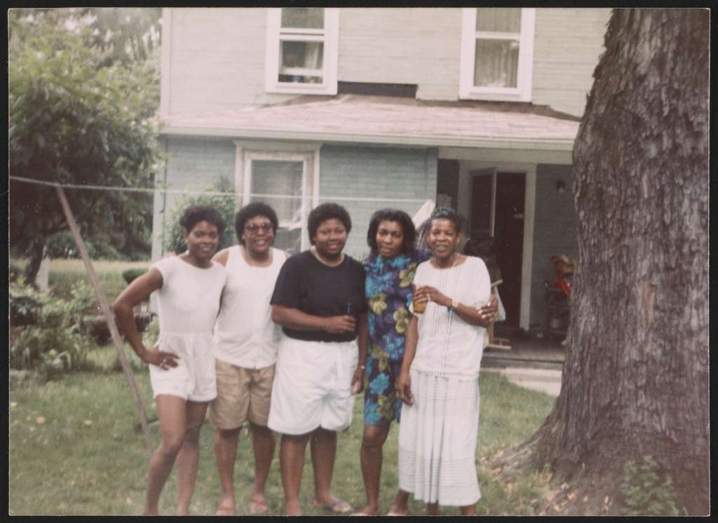 Five Black American-appearing women standing in the front yard, could be anytime mid 1970s-1990s, easily
