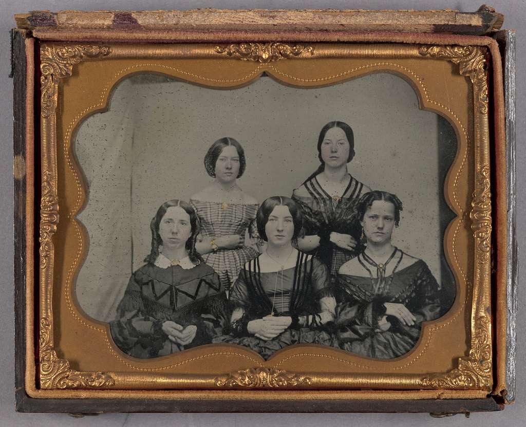 Five white women sitting for a portrait, black and white photo, gold frame, ca. 1860s-type clothing. Very Little Women.