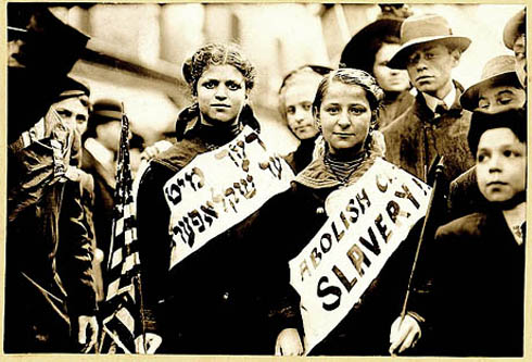 Two girls wearing badges in English and Yiddish: abolish child slavery! 