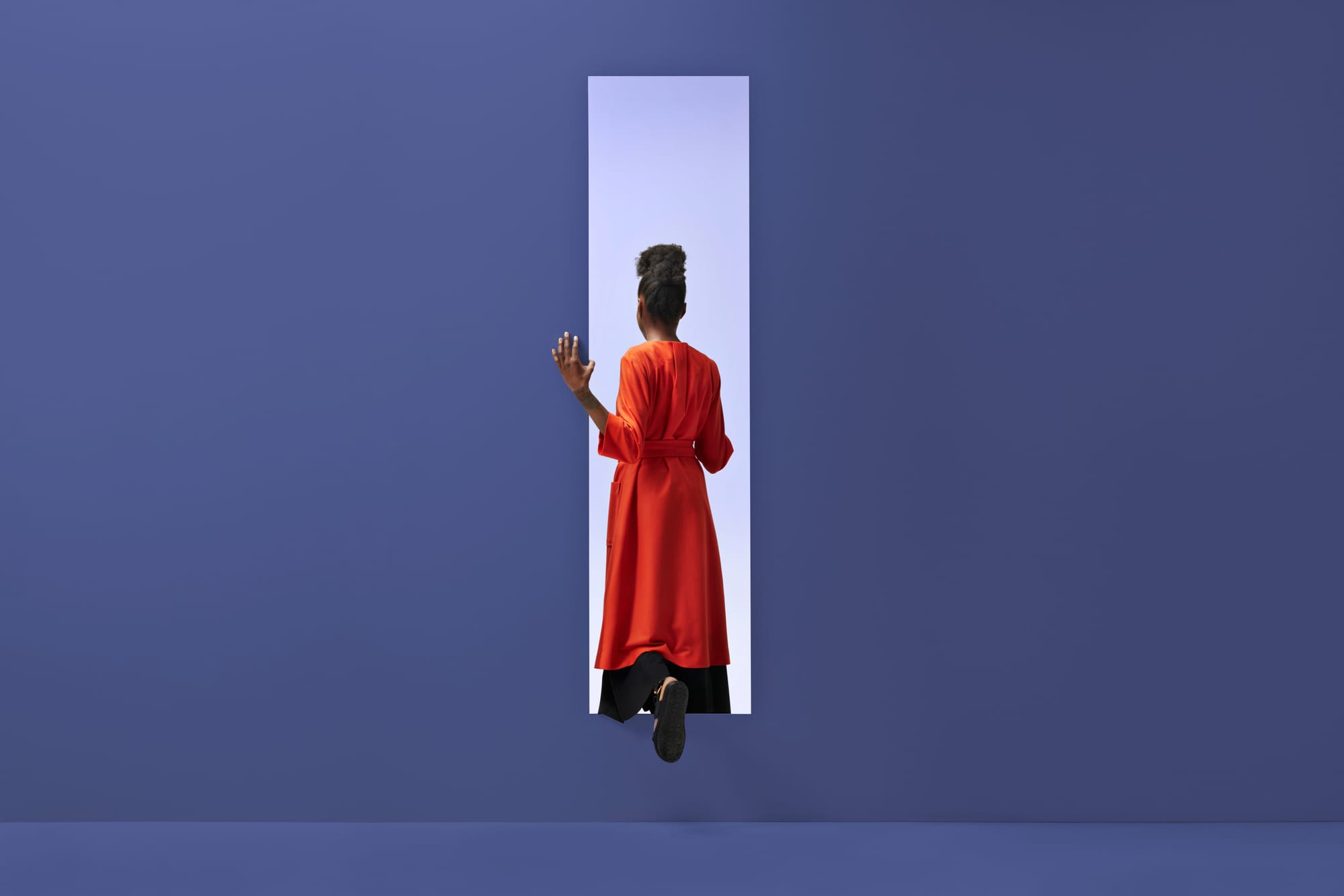 Black person with orange cloak stepping through portal in purple background