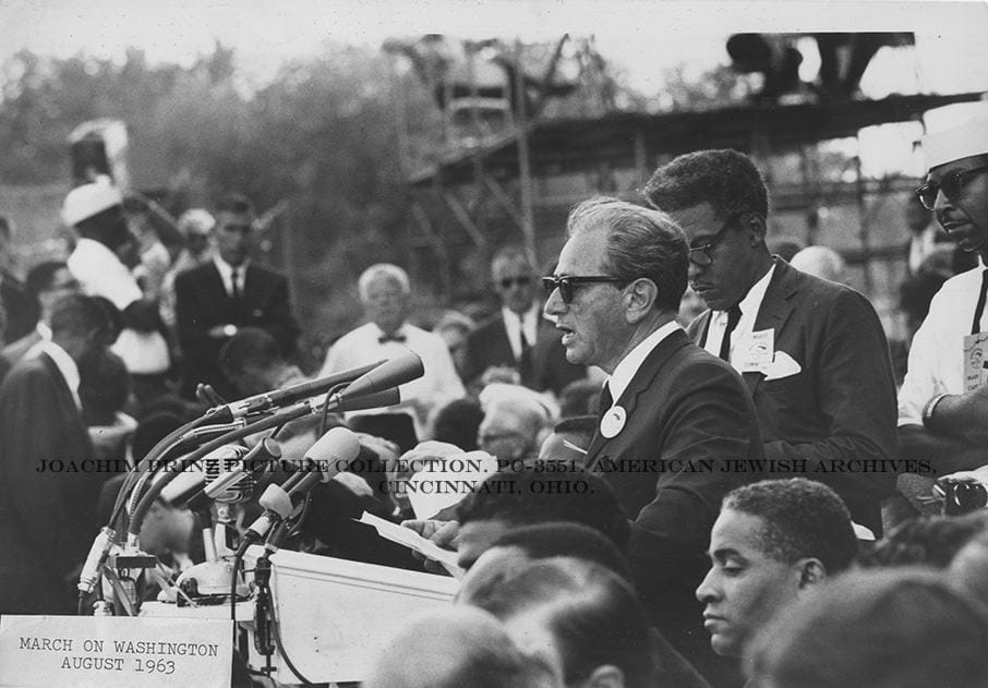 Joachim Prinz in black and white speaking into mics 