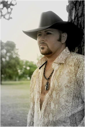 Photo of a white masc person with a goatee and a cowboy hat outside, looking pensive