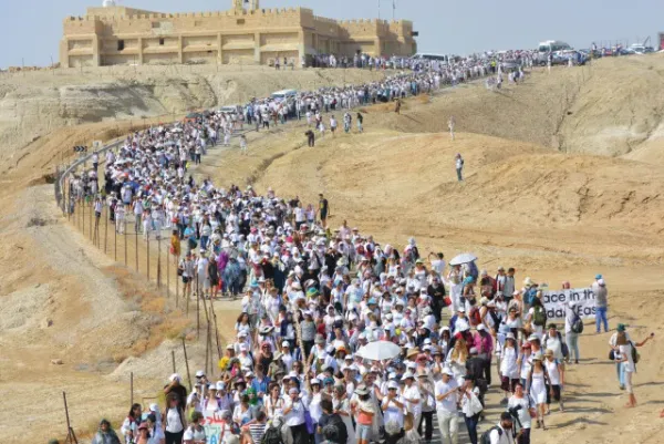 Lots of people in the desert walking in white 