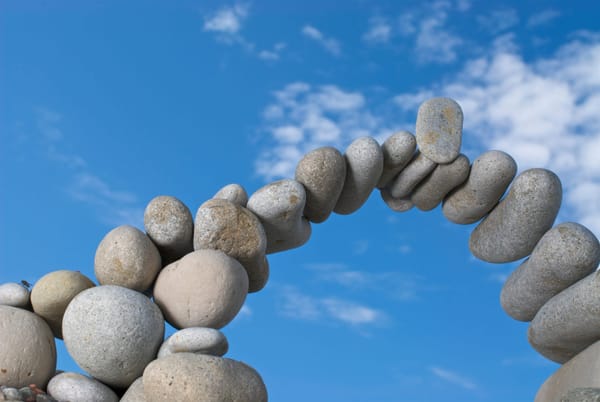 Image of an arch of stones piled against a blue sky