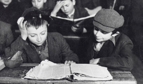 Two young kids in black and white studying a tattered Talmud together 